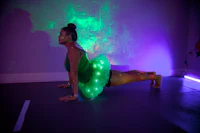 a woman in a green tutu doing a pose in front of a green light